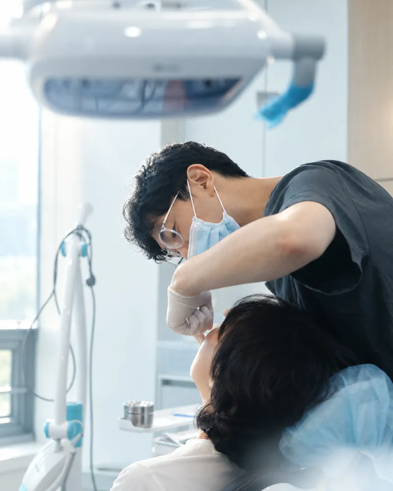 진료 의자의 환자를 가까이 살피는 원장